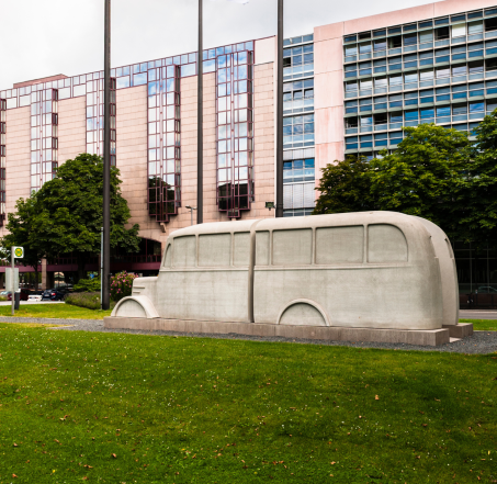 Man sieht einen grauen Steinbus, das Denkmal der grauen Busse, auf der Wiese vor dem Deutzer Landeshaus.